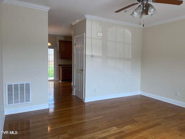 empty room with baseboards, visible vents, wood finished floors, and ornamental molding