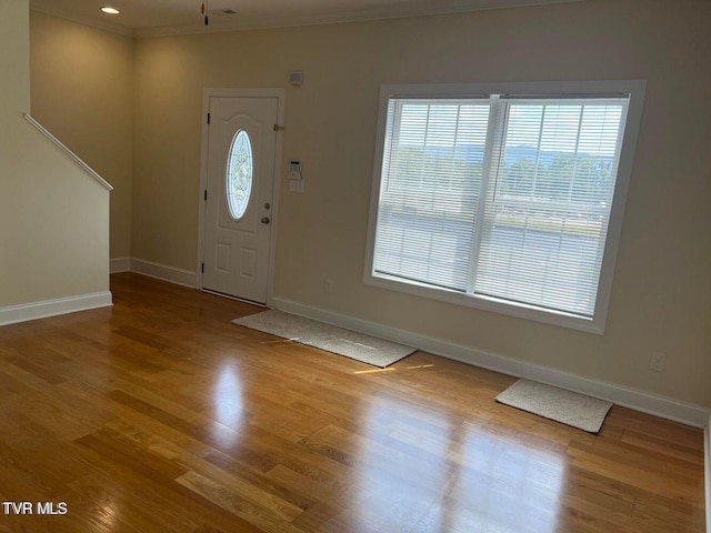 entryway with ornamental molding, baseboards, and wood finished floors