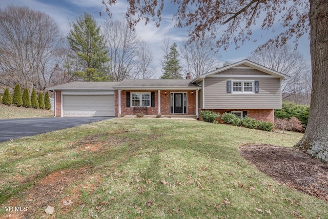 split level home with aphalt driveway, brick siding, a garage, and a front yard