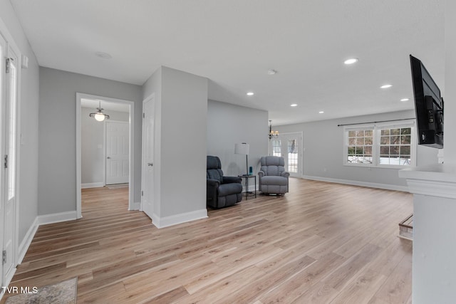 unfurnished room featuring light wood finished floors, recessed lighting, an inviting chandelier, and baseboards