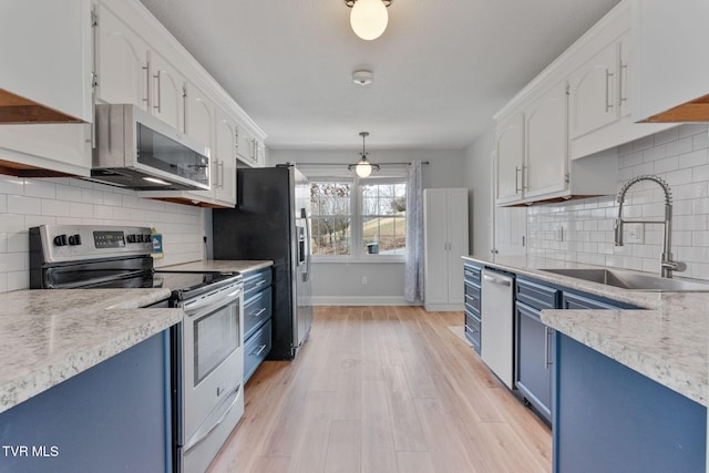 kitchen with blue cabinetry, a sink, light countertops, appliances with stainless steel finishes, and white cabinetry