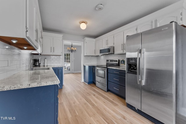 kitchen featuring blue cabinetry, white cabinets, stainless steel appliances, and light wood-type flooring