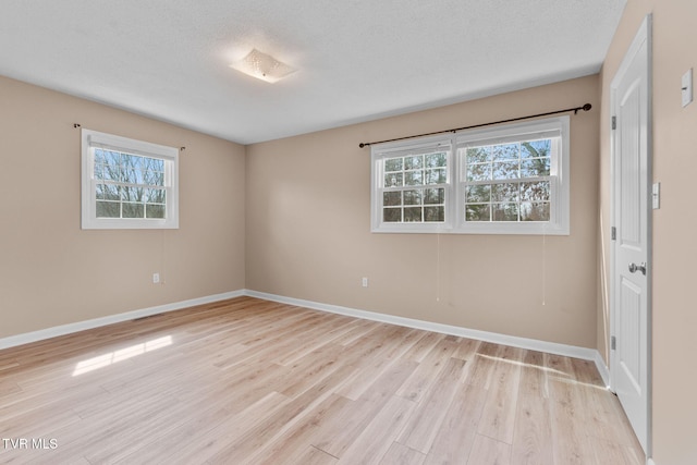 empty room featuring plenty of natural light, light wood-style floors, and baseboards