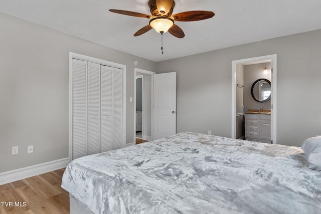 bedroom featuring baseboards, light wood-type flooring, ensuite bathroom, a closet, and a sink