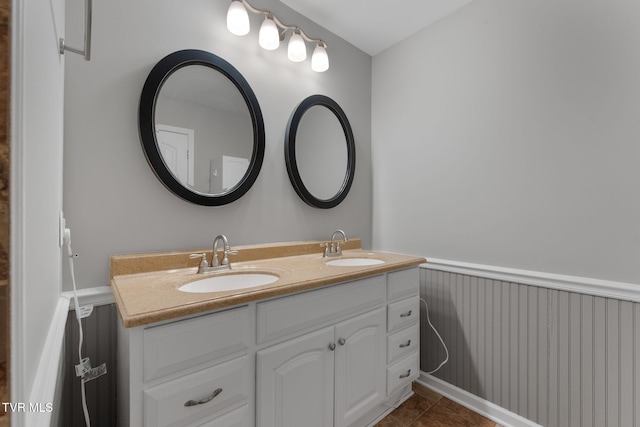 bathroom featuring a sink, a wainscoted wall, double vanity, and tile patterned flooring