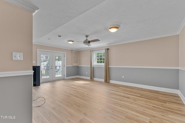 unfurnished living room with a ceiling fan, french doors, crown molding, light wood finished floors, and baseboards