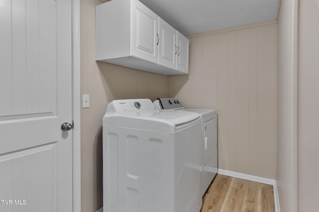 washroom featuring light wood-style flooring, cabinet space, baseboards, and washing machine and dryer