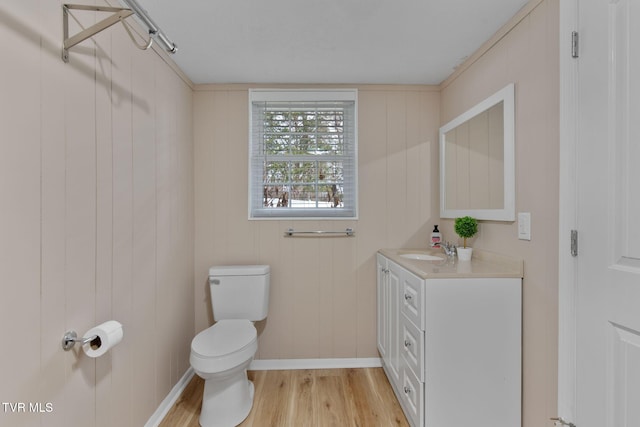 bathroom featuring vanity, toilet, wood finished floors, and baseboards