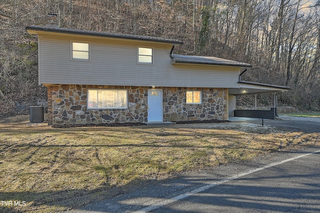 view of front facade with central air condition unit, concrete driveway, stone siding, a carport, and a front yard