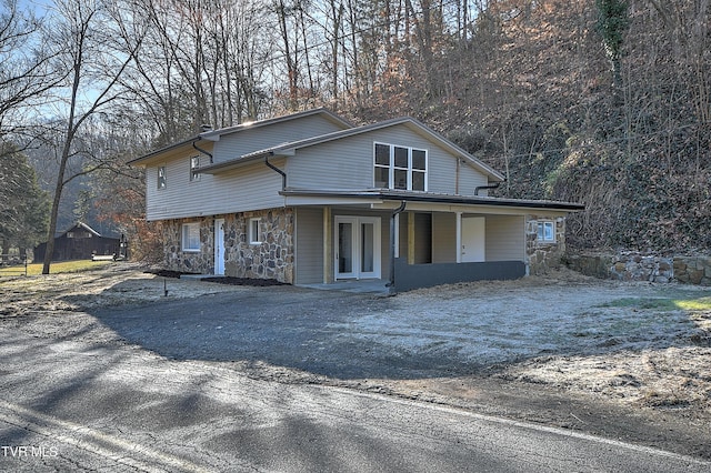 view of front of home with driveway, stone siding, and french doors