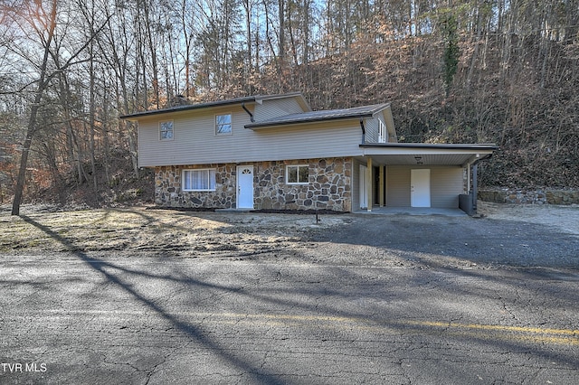 view of front of home with stone siding, aphalt driveway, and a carport