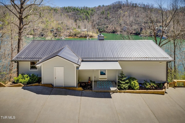 view of front of home with metal roof, a standing seam roof, a water view, and a wooded view