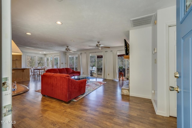 living area with baseboards, visible vents, wood finished floors, and recessed lighting