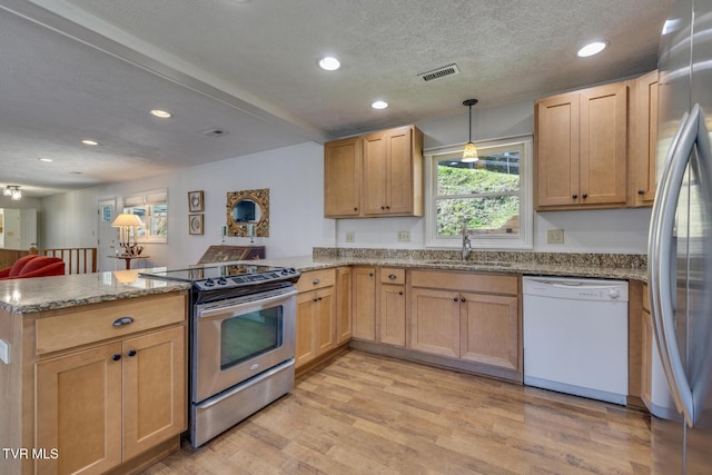 kitchen with light wood finished floors, visible vents, appliances with stainless steel finishes, a peninsula, and a sink