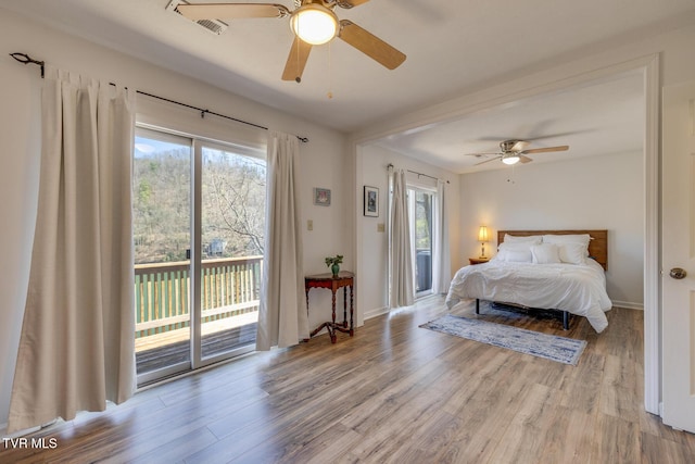 bedroom with access to exterior, multiple windows, a ceiling fan, and wood finished floors