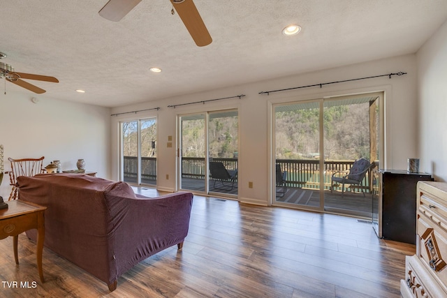 living room with a ceiling fan, recessed lighting, a textured ceiling, and wood finished floors