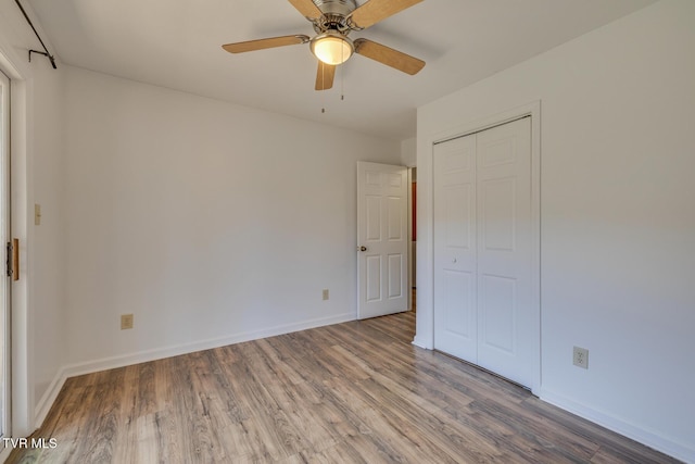 unfurnished bedroom with a ceiling fan, a closet, baseboards, and wood finished floors