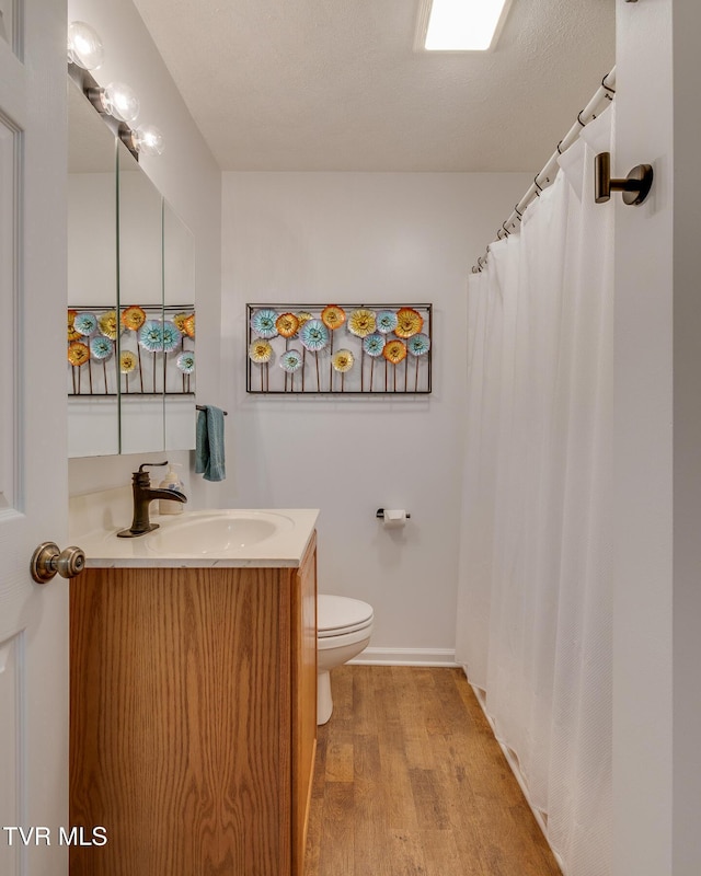 bathroom with vanity, wood finished floors, toilet, and baseboards