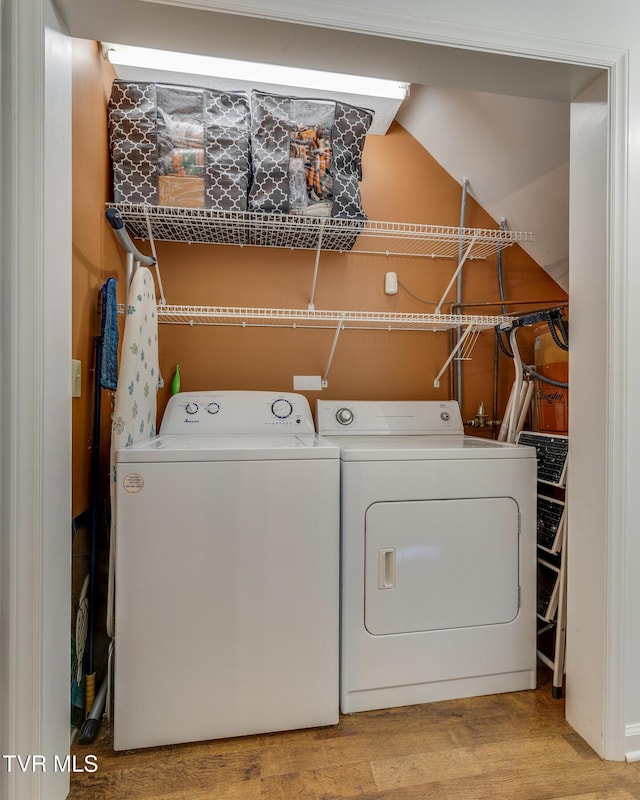 laundry area with laundry area, washing machine and dryer, and wood finished floors