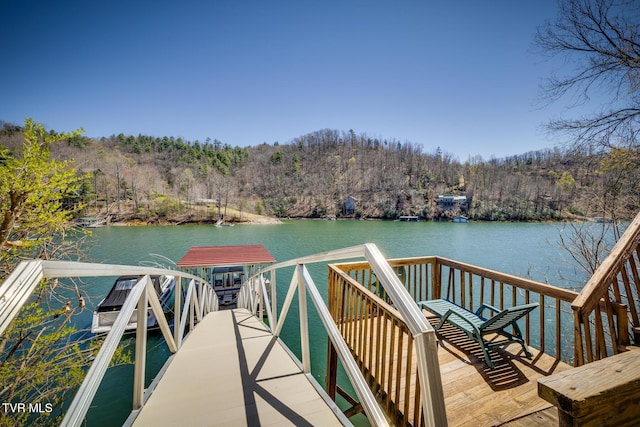 view of dock with a forest view and a water view