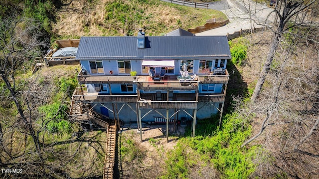 back of property with a chimney, metal roof, and stairway