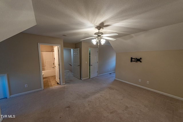 bonus room with lofted ceiling, ceiling fan, a textured ceiling, and baseboards