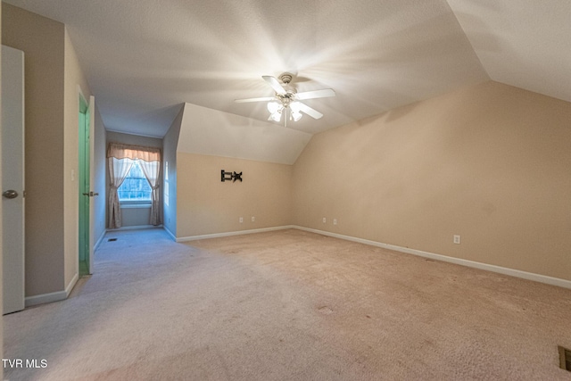 additional living space with light carpet, baseboards, visible vents, lofted ceiling, and ceiling fan