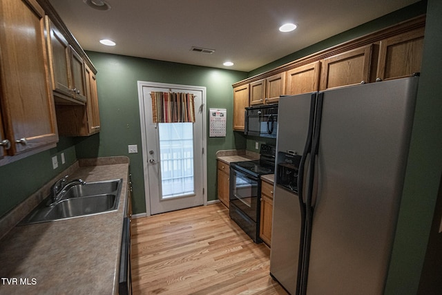 kitchen featuring recessed lighting, a sink, visible vents, black appliances, and light wood finished floors