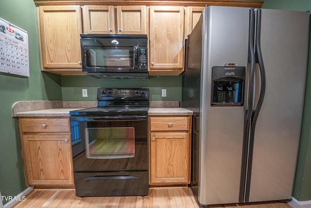 kitchen with baseboards, black appliances, light countertops, and light wood-style floors