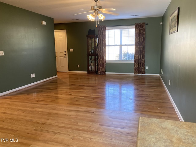 spare room with ceiling fan, wood finished floors, and baseboards