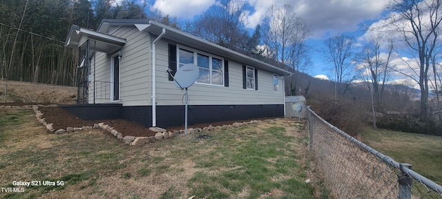 view of side of property with crawl space, fence, and a lawn