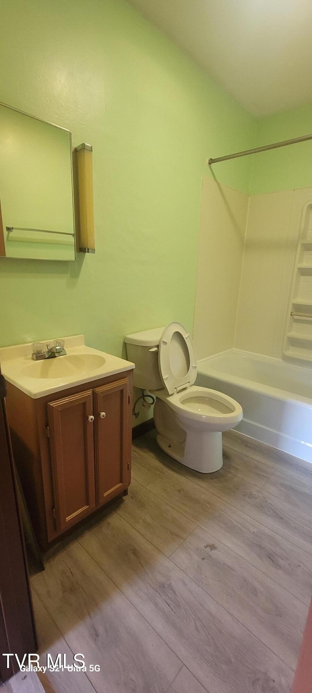 bathroom featuring washtub / shower combination, vanity, toilet, and wood finished floors