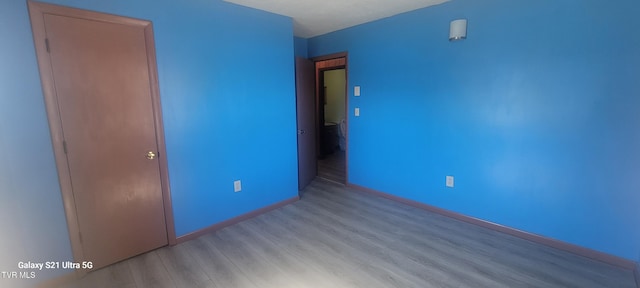 unfurnished bedroom with wood finished floors and baseboards