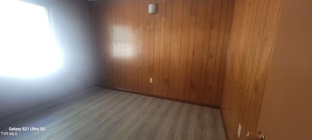 spare room featuring wood walls, baseboards, and wood finished floors