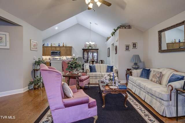 living area with vaulted ceiling, ceiling fan with notable chandelier, wood finished floors, and baseboards