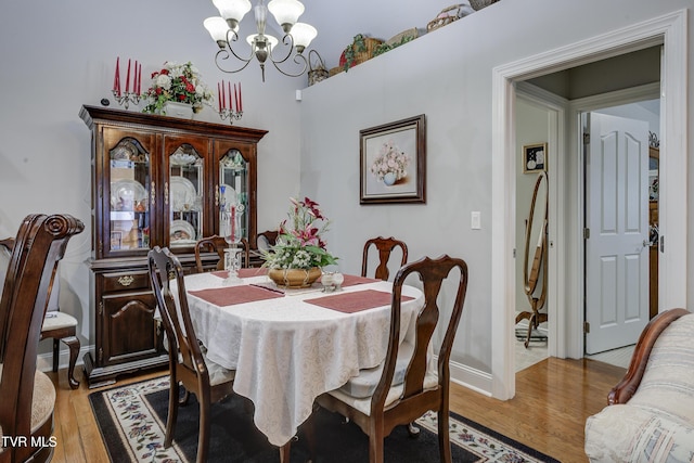 dining area with baseboards, light wood-style flooring, and an inviting chandelier