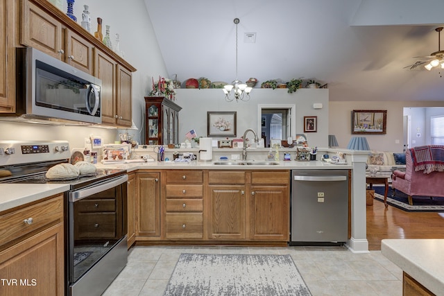 kitchen with appliances with stainless steel finishes, open floor plan, a sink, vaulted ceiling, and a peninsula