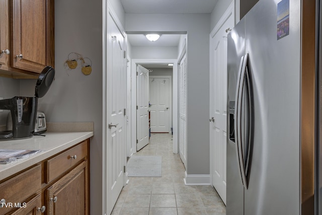 kitchen featuring light countertops, brown cabinets, stainless steel fridge with ice dispenser, and light tile patterned flooring