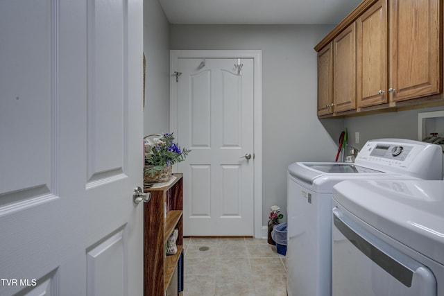 washroom featuring light tile patterned floors, washing machine and clothes dryer, and cabinet space