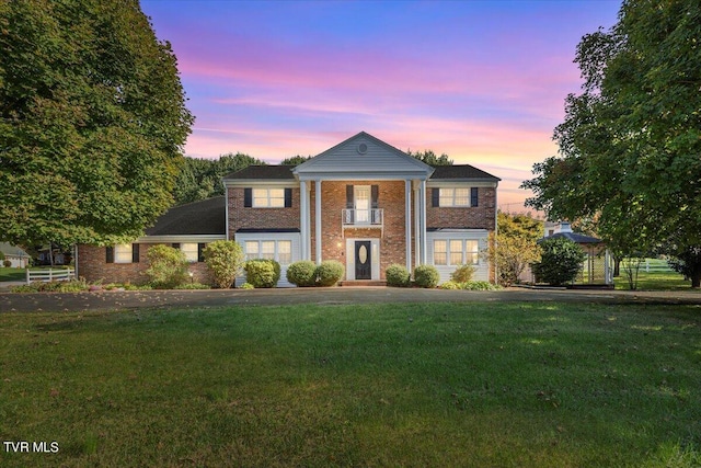 greek revival inspired property featuring a lawn and brick siding