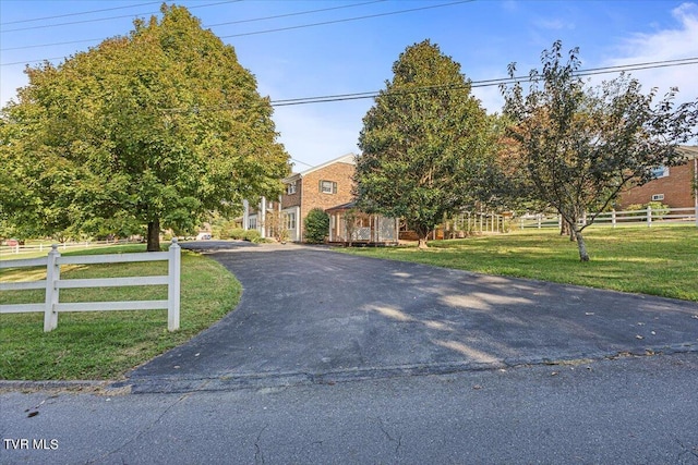 view of front of home featuring driveway, fence, and a front lawn