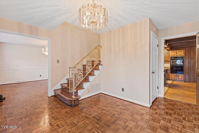 interior space featuring a chandelier, a textured ceiling, stairs, and baseboards