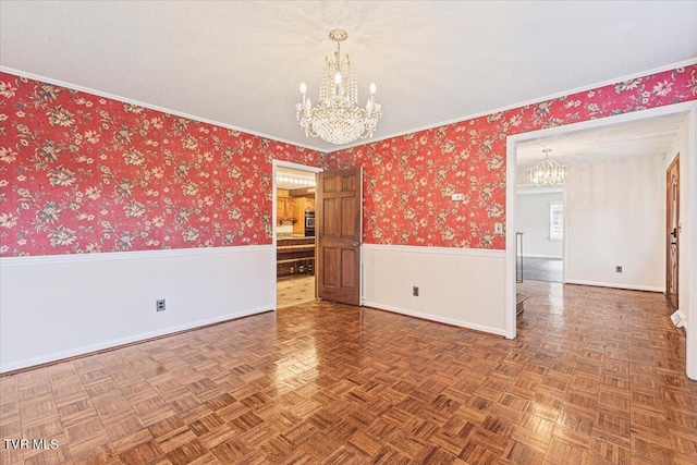 empty room with baseboards, wallpapered walls, wainscoting, and an inviting chandelier