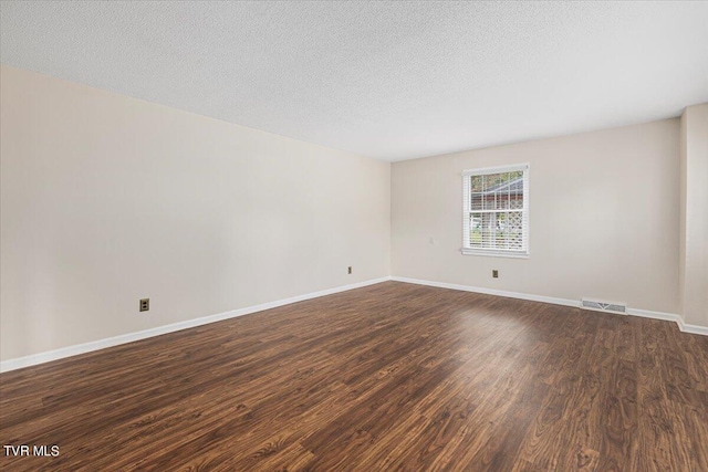 spare room featuring visible vents, dark wood finished floors, and baseboards