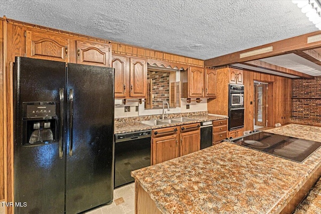 kitchen with a textured ceiling, a sink, brown cabinets, black appliances, and beamed ceiling