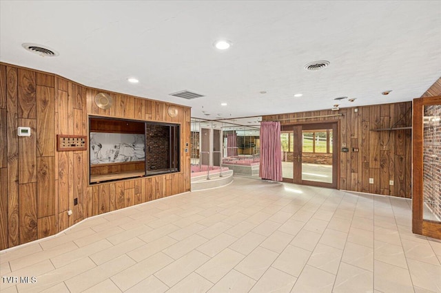 unfurnished living room featuring visible vents and wooden walls