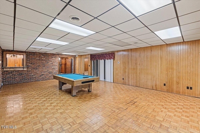 recreation room with a paneled ceiling, wooden walls, brick wall, pool table, and visible vents