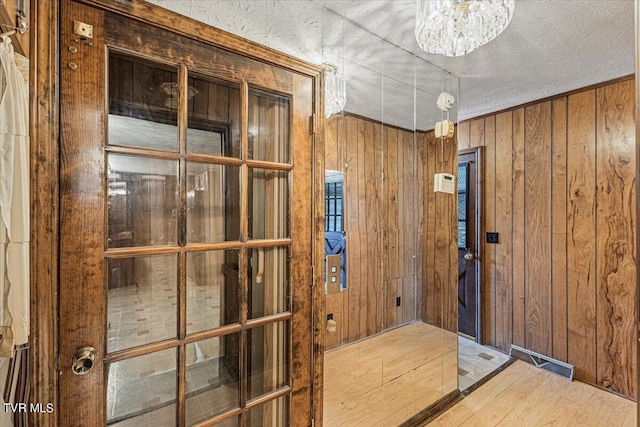 doorway to outside featuring an inviting chandelier, wooden walls, and wood finished floors