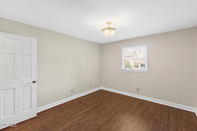 unfurnished room with baseboards and dark wood-style flooring