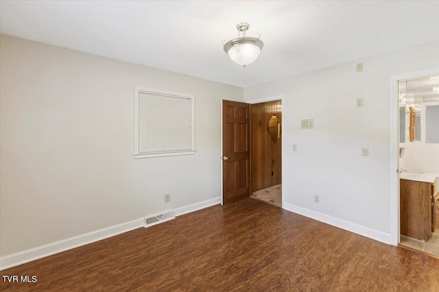 unfurnished bedroom featuring wood finished floors, visible vents, and baseboards